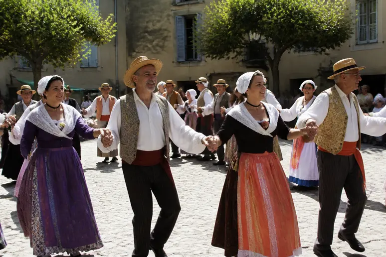 Des villageois provençaux en costume traditionnel dansent la farandole, symbolisant l'unité et la joie collective.