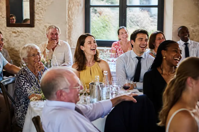 Comment choisir citation mariage : invités riant complices lors d'une réception, montrant l'originalité de l'événement.