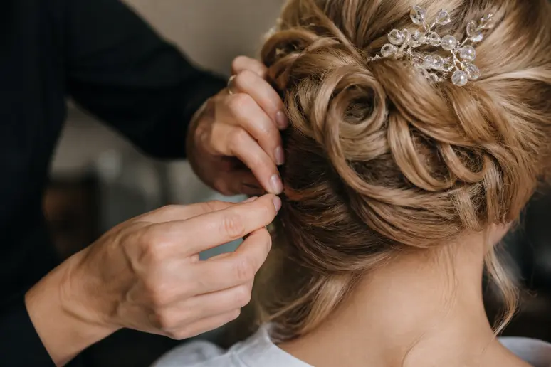 Mains fixant une coiffure de mariage sur cheveux longs avec des épingles