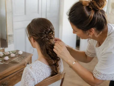 Une mariée aux longs cheveux bouclés reçoit une coiffure mariage cheveux longs tressée par un professionnel à Chartres.