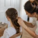Une mariée aux longs cheveux bouclés reçoit une coiffure mariage cheveux longs tressée par un professionnel à Chartres.