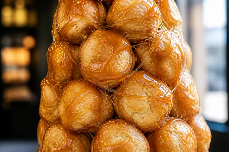 Pyramide de choux dorés assemblés par du caramel pour former un croquembouche traditionnel