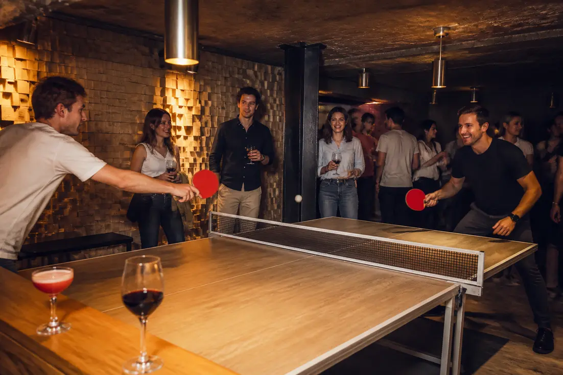 Amis jouant au ping-pong et riant lors d'une soirée privée au Gossima ping pong bar Paris