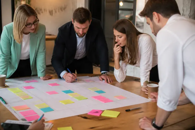 Mains d'organisateurs planifiant les dates clés pour organiser un séminaire d'entreprise sur un tableau