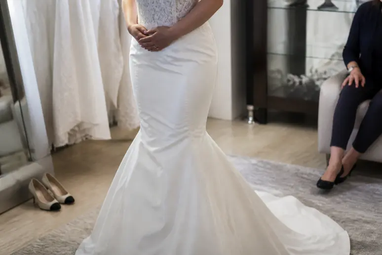 Mariée essayant une robe de mariée sirène cintrée mettant en valeur les courbes.