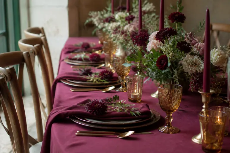 Décoration de table raffinée avec du linge de maison pourpre et de la verrerie ambrée.