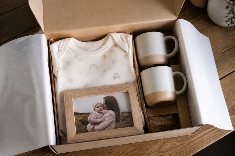 Coffret cadeau ouvert pour annonce de grossesse contenant des mugs et un body