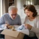 Un couple de futurs grands-parents découvrant de superbes idées cadeaux annonce grossesse grands-parents dans un salon lumineux.