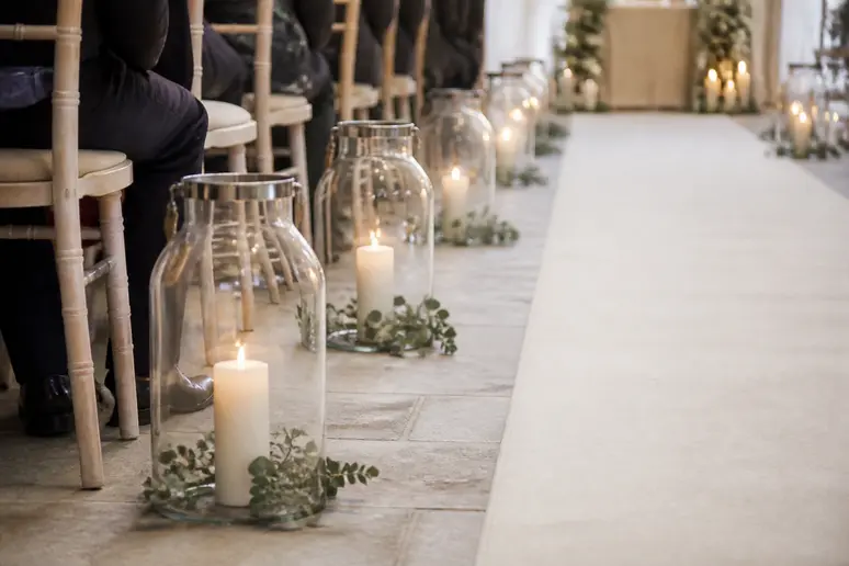 Grands photophores en verre installés au sol le long de l'allée d'une cérémonie de mariage