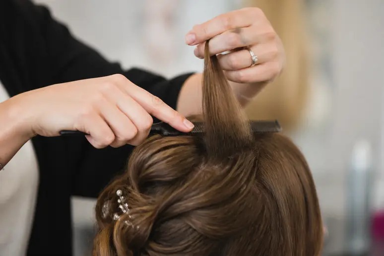 Coiffeur réalisant un crêpage des racines pour donner du volume à une coiffure de mariage
