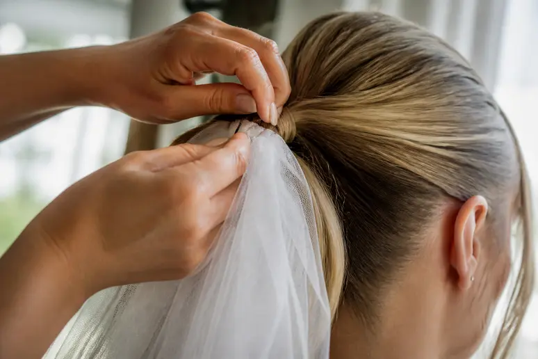Fixation d'un voile de mariée sur une queue de cheval haute avec des épingles