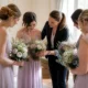 Quatre demoiselles d'honneur en robes pastel préparent leurs bouquets pour un mariage, illustrant combien de demoiselles d'honneur choisir.