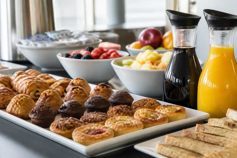 Assortiment de mini-viennoiseries et carafes de jus pour un petit-déjeuner d'entreprise en salle de réunion