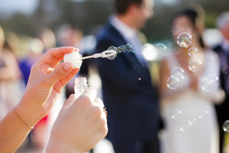 Invités soufflant des bulles de savon sur le parvis lors d'une sortie de mariage
