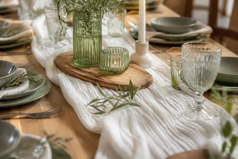 Chemin de table en gaze de coton blanche froissé avec souplesse sur une table de fête en bois