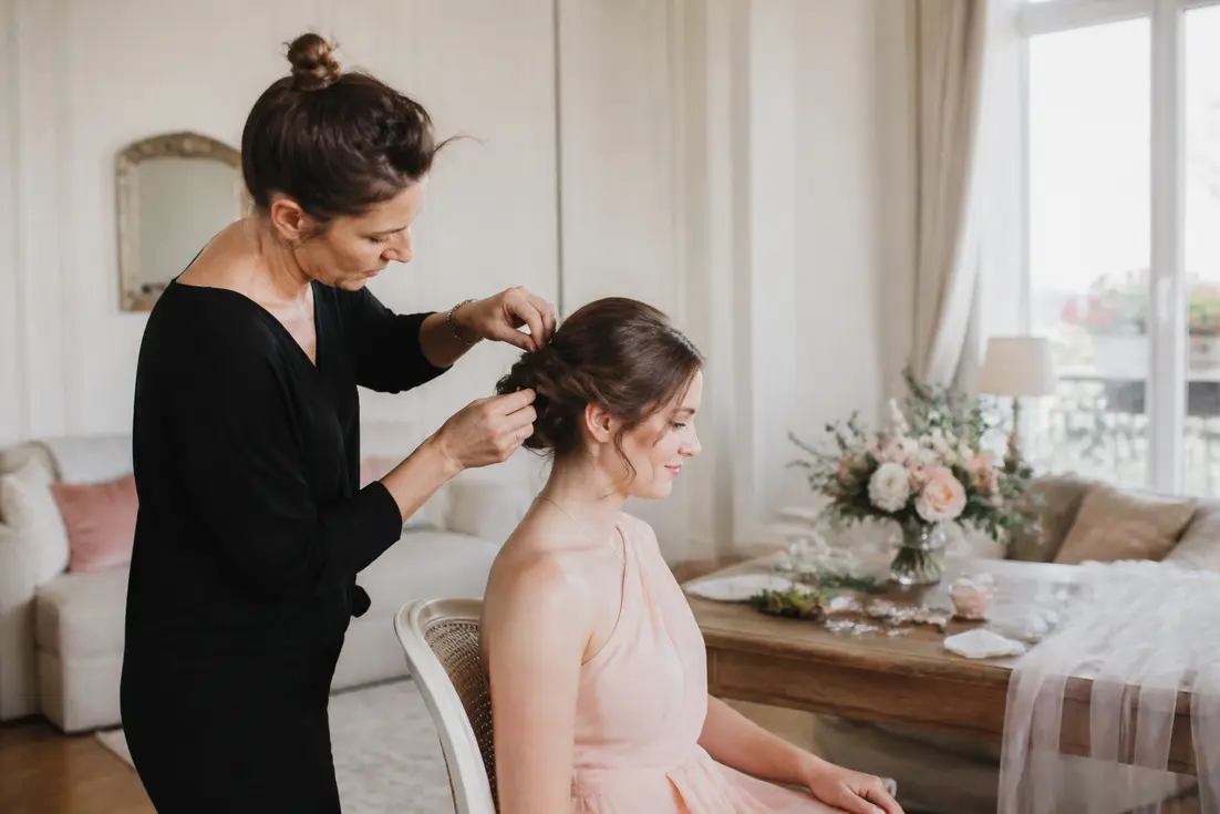 Un coiffeur demoiselle d'honneur prépare la mise en beauté d'une participante avant la cérémonie de mariage.