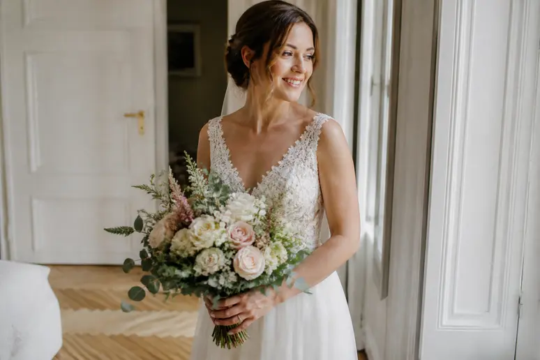 Mariée tenant son bouquet de fleurs adapté à sa silhouette avant la cérémonie