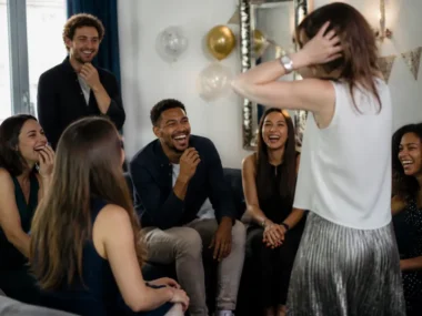 Amis riant ensemble lors d'une fête avec des jeux pour anniversaire adulte rigolo dans un salon chaleureux