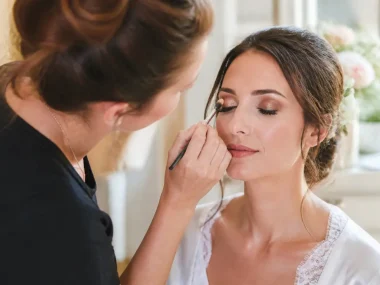 maquillage mariage yeux marrons appliqué avec délicatesse par une professionnelle dans un salon lumineux