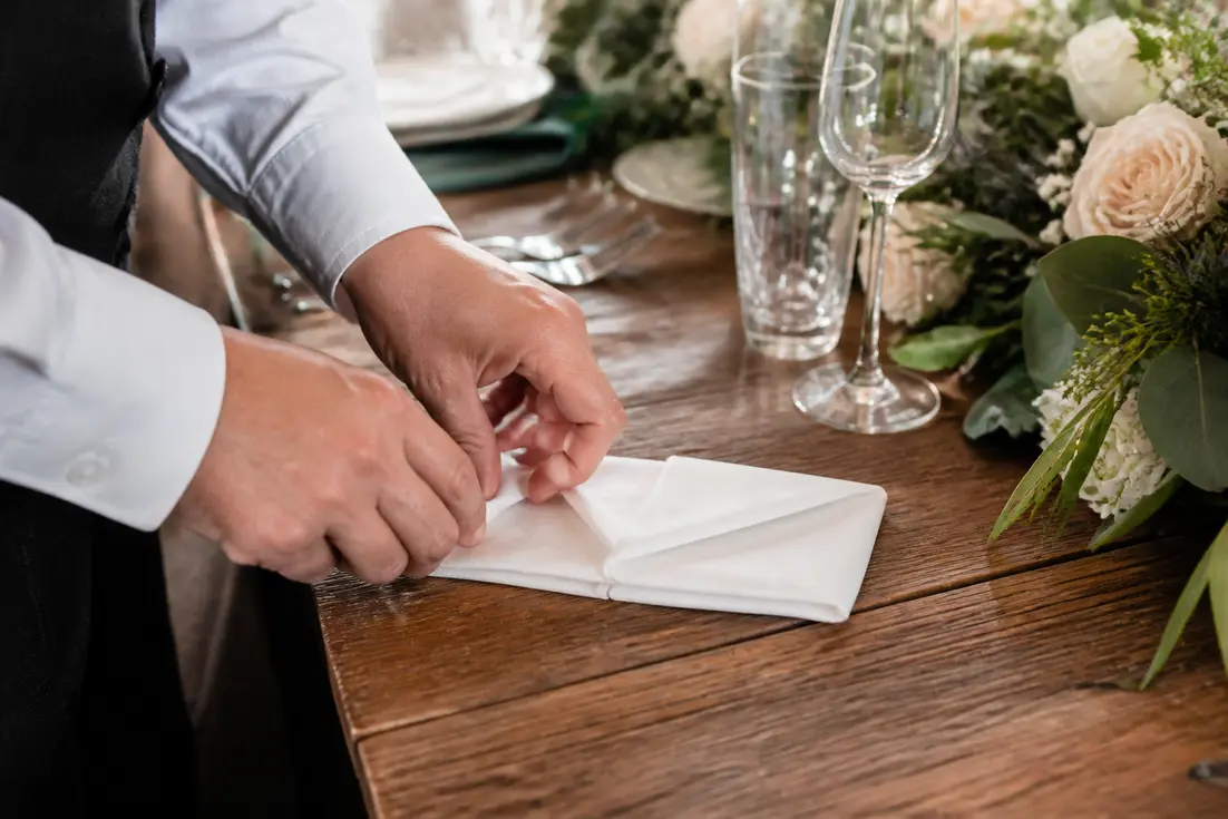 Mains en train de réaliser un pliage serviette en papier pour une table de mariage à Chartres