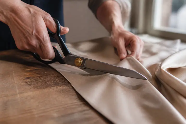 Ciseaux de couturière coupant une pièce de tissu en soie sur une table d'atelier