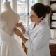 Un atelier de couture parisien où une créatrice ajuste les détails d'un prix robe de mariée luxe en soie.